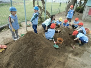 画像：赤い帽子は年中組 「先生と一緒に力を合わせてトンネル作り」